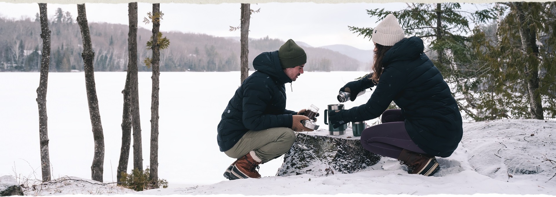Two people pouring coffee  in a wintery landscape.